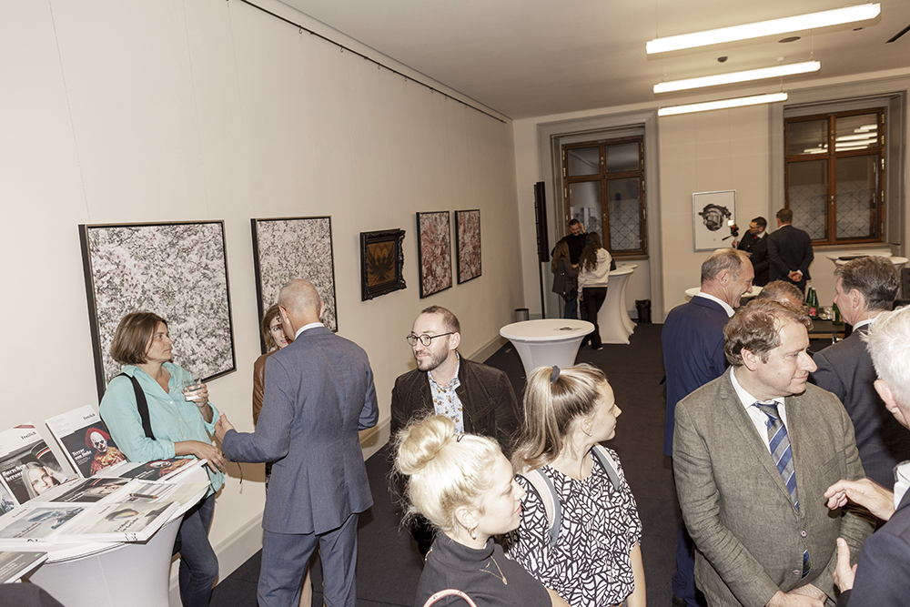 Vernissage der Ausstellung "Gerhard Rihl, Personale 2023": Besuchergruppen vor dem Bildzyklus "En fleur", der Arbeit "Banner des Heiligen Römischen Reiches in Federn", sowie der Arbeit "Stierschädel I".